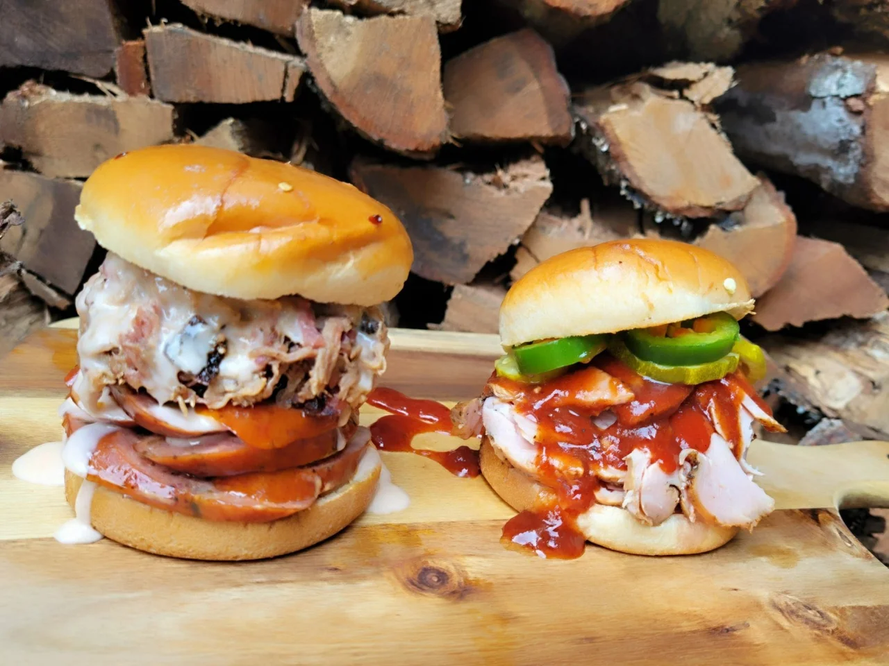 Two CorkScrew barbecue sandwiches in front of stacked oak firewood