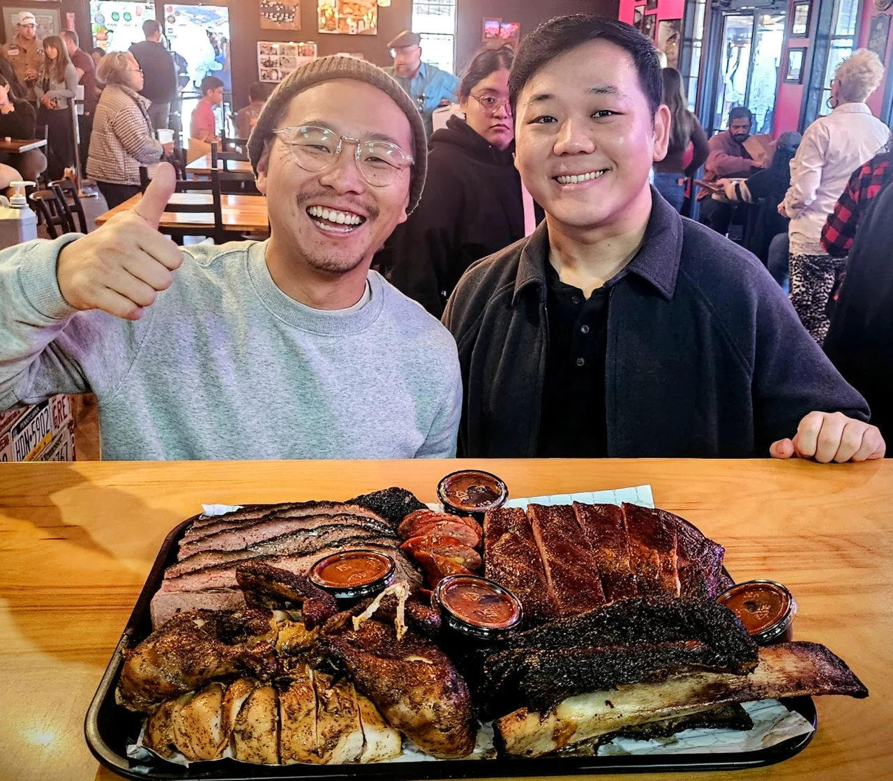 Two guests sharing a tray of CorkScrew brisket, ribs, and sausage
